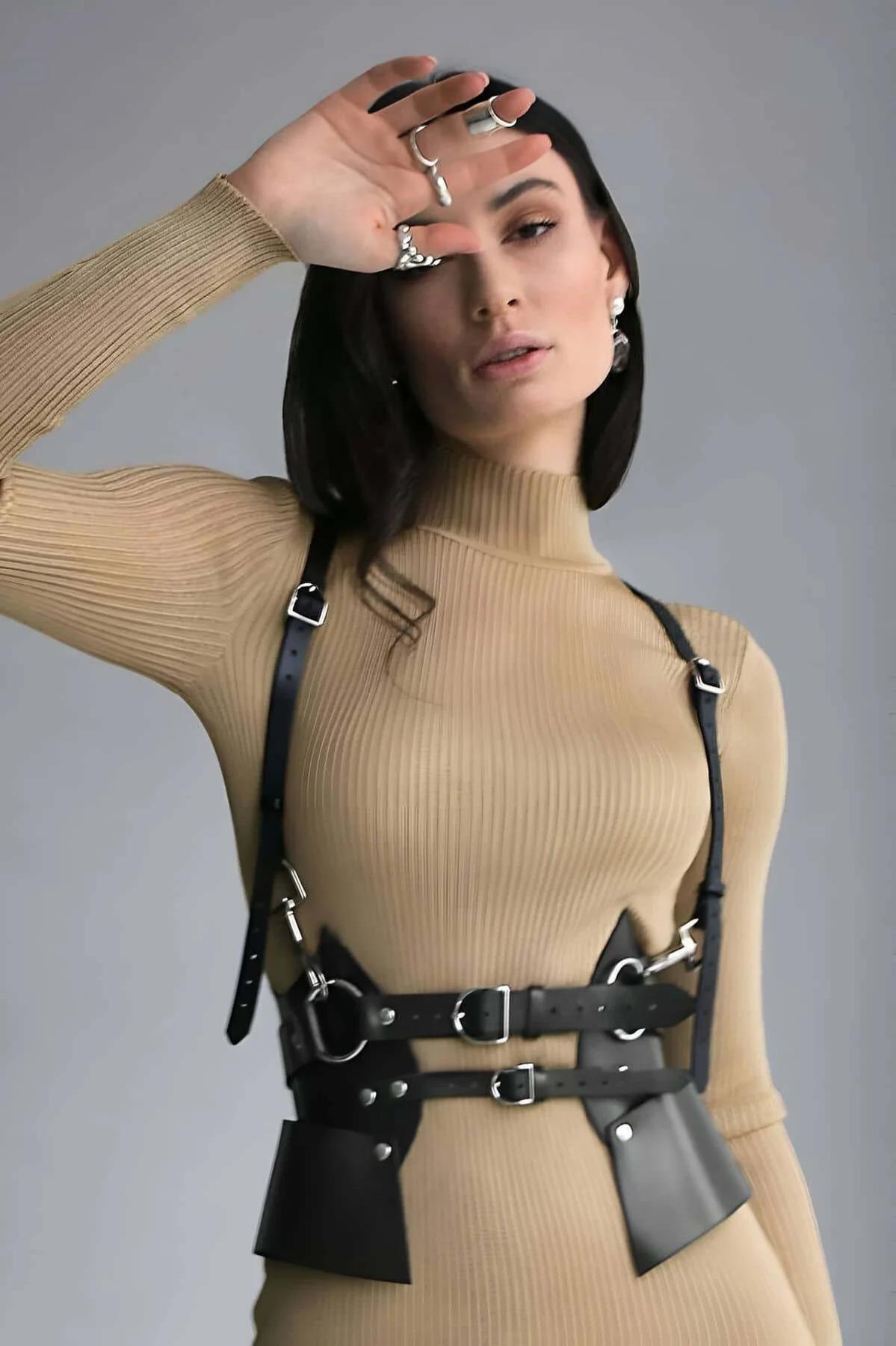 deve tüyü renkli nervürlü boğazlı kazak üzerine giyilen siyah suni deri oyma vücut harness, geniş bel panelleri ve gümüş tokalar