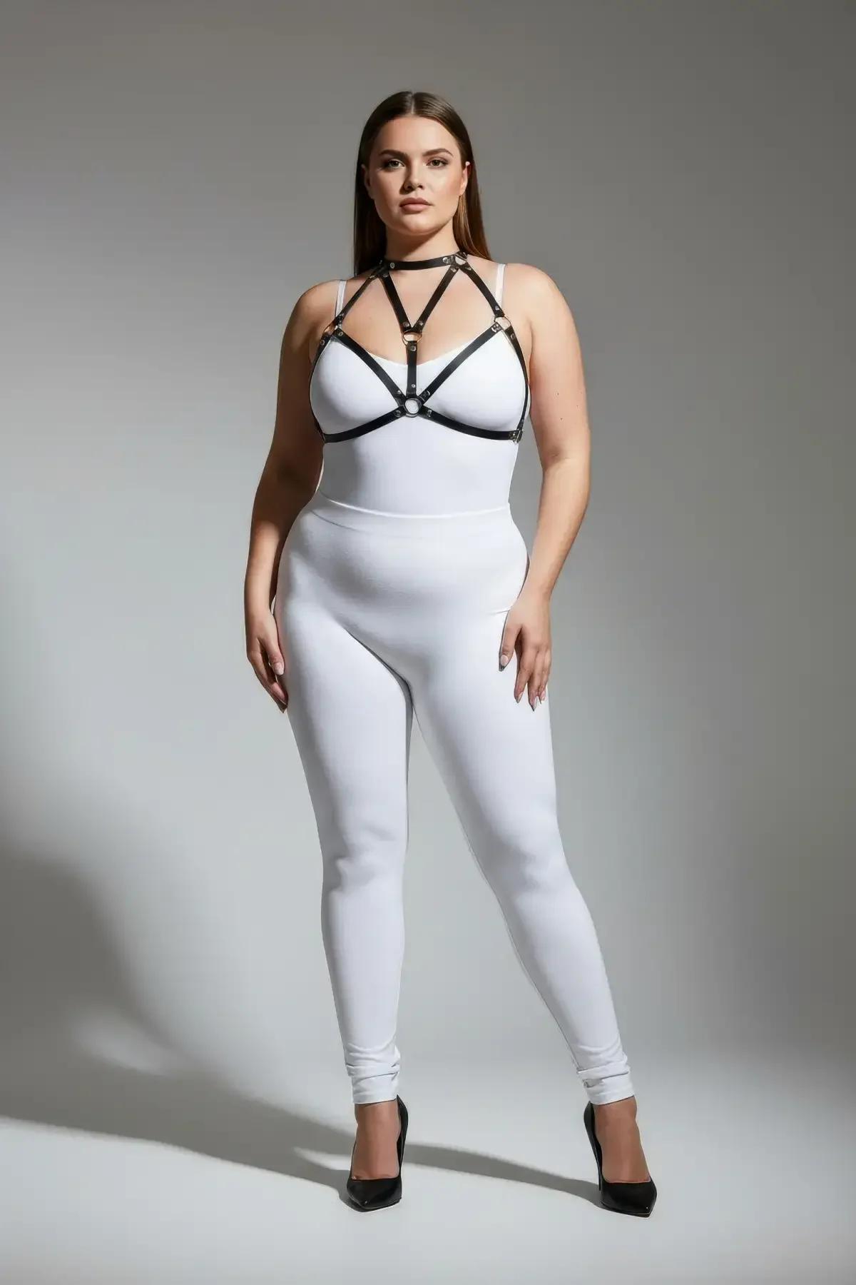 Beyaz bodysuit üzerinde altın O-halka detaylı siyah suni deri bantlı vücut harness, üçgen göğüs bant konfigürasyonu