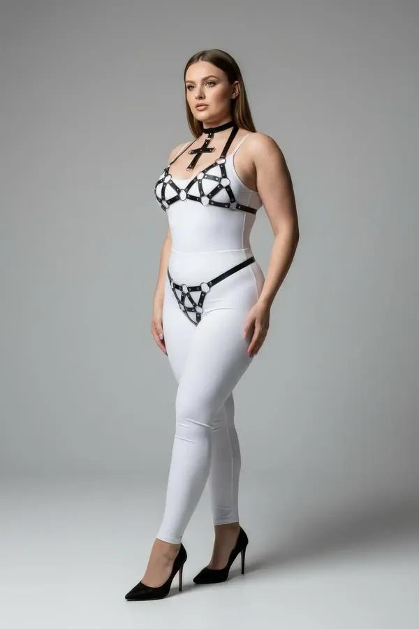 Çapraz çoker, geometrik gümüş O-halka göğüs harness ve kalça G-string içeren siyah suni deri 3 parçalı harness takımı, beyaz üzerinde