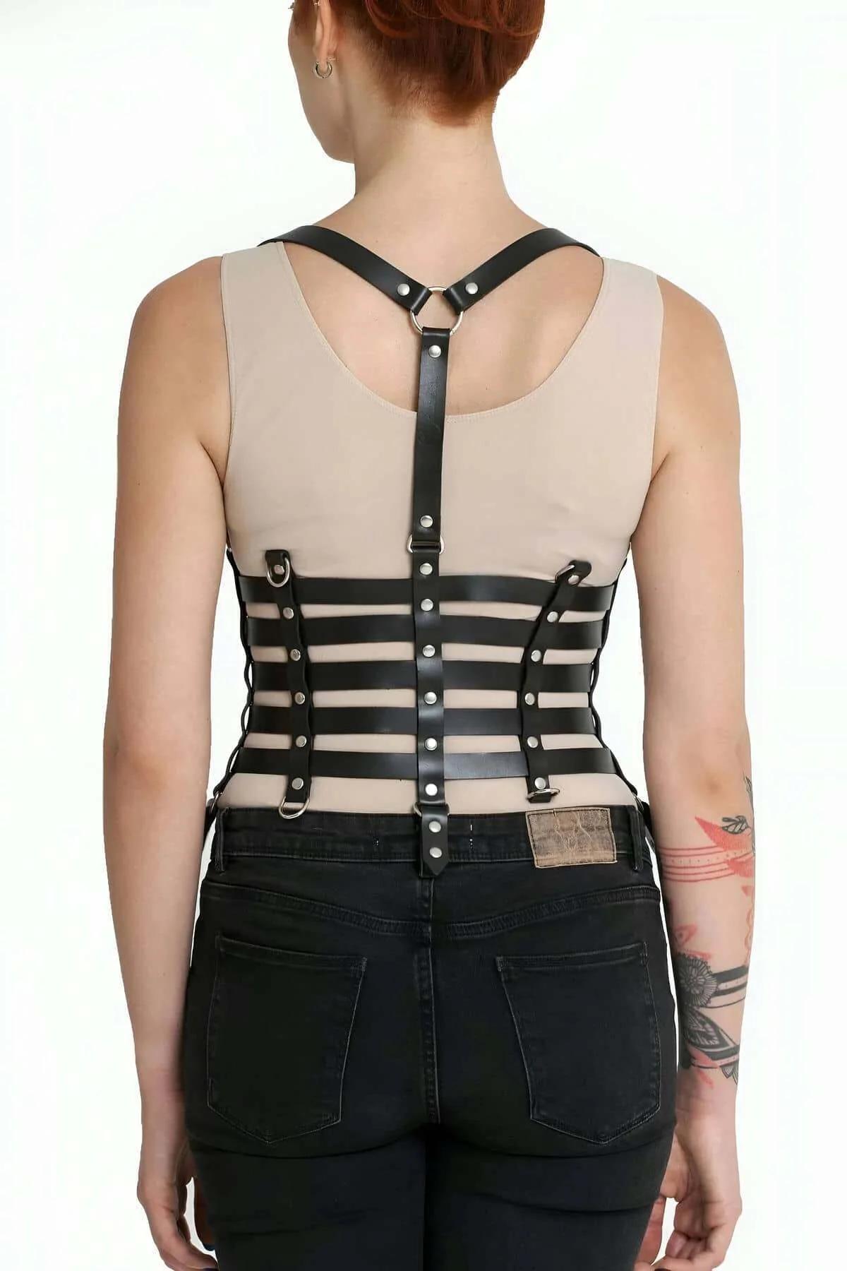 Siyah kot ve bej üst üzerine giyilen D-halkalı siyah beş bantlı korse harness, yan açı
