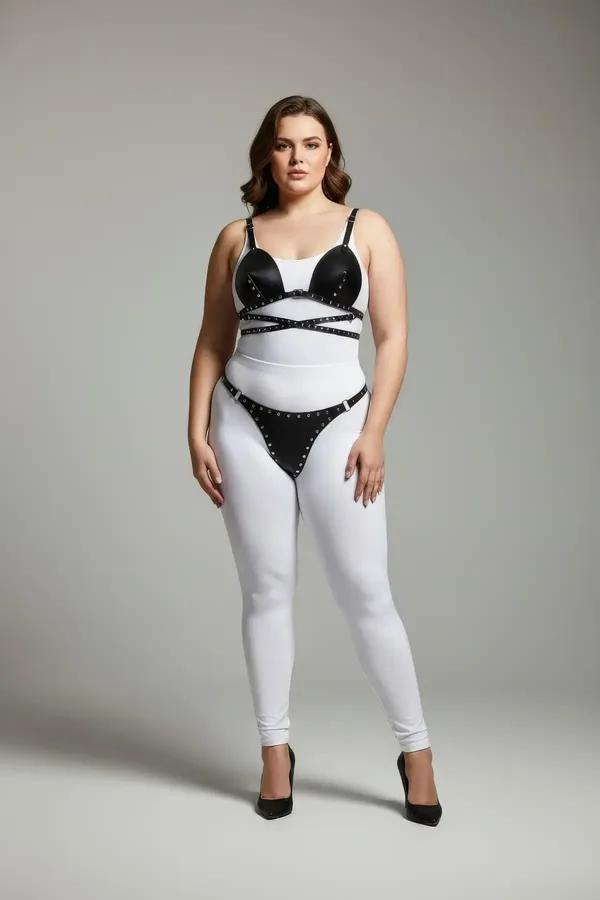 Beyaz tayt üzerinde modellenen gümüş zımba süslemeli siyah suni deri zımbalı sütyen üst ve tanga harness takımı