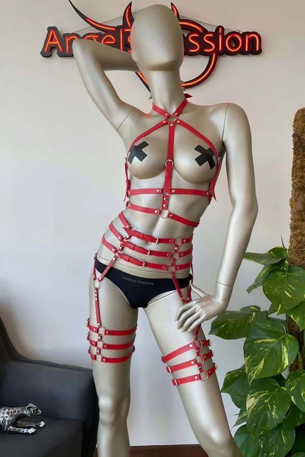 Manken üzerinde istiflenmiş uyluk jartiyerleri ve gümüş O-halka toka donanımlı kırmızı suni deri çok askılı tam vücut harness